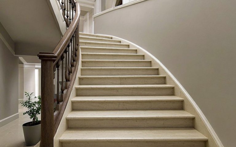 Eine geschwungene Treppe mit hellen Stufen und einemHolzgeländer in einem modernen Raum.